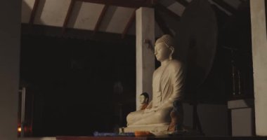 Huzurlu bir Buda heykeli, gece huzurlu bir tapınak ortamında çekilen canlı halo ışıklarıyla aydınlatılıyor. Maneviyat, meditasyon ve dini sembolizm konuları için mükemmel.. 