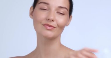 Kusursuz, parıldayan cildi nazikçe okşayan kendine güvenen bir kadının yakın çekimi. Lüks güzellik kampanyaları, cilt bakım ürünleri promosyonları ve spa konseptleri için mükemmel.. 