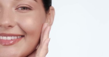 Yüzüne nazikçe dokunan parlak, sağlıklı bir cilde sahip gülümseyen bir kadının yakın çekimi. Cilt reklamları, güzellik konseptleri ve lüks kozmetik ürünleri promosyonları için ideal.. 