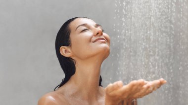  Barışçıl bir ifadeye ve kapalı gözlere sahip bir kadın ferahlatıcı bir duştan zevk alır, dinginlik ve kendine bakım anının altını çizer. Zenginlik, cilt bakımı ve gençleşme konuları için mükemmel.. 