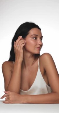 Beyaz bluzlu, parlak tenli, altın halkalı küpeli ve doğal makyajlı zarif bir kadın. Cilt bakımı, moda ve güzellik kampanyaları için ideal.. 