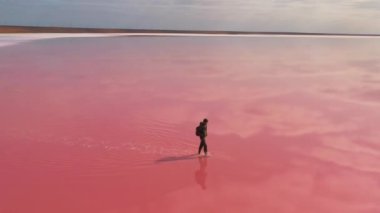 Sırt çantalı yalnız bir gezgin dinginlikle çevrili canlı pembe bir tuz gölünde zarifçe yürüyor. Keşif, macera ve doğal güzelliğin özünü yakalar.. 