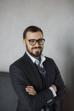 Gözlüklü gülümseyen genç bir adamın portresi ve kolları katlanmış resmi bir takım elbise. Şirket, iş ve liderlik temalı fotoğrafçılık için mükemmel.. 