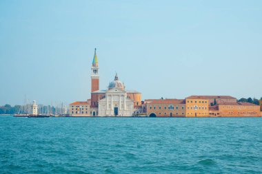 İtalya 'nın Venedik kentindeki San Giorgio Maggiore adasının ikonik çan kulesi ve sakin sularla çevrili tarihi mimarisinin pitoresk bir manzarası. Seyahat ve kültürel temalar için mükemmel. 