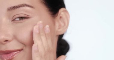 Gülümseyen bir kadının, kusursuz, parıldayan tenine nazikçe dokunduğu, doğal güzelliğini ve cildini gösteren yakın plan fotoğrafı. Güzellik, sağlık ve kişisel bakım için mükemmel.. 