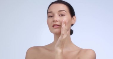 Yüzüne hafifçe dokunan kusursuz ciltli güzel bir kadın gülümserken, cildini ve özgüven kavramlarını ön plana çıkarırken. Güzellik, sağlık ve kozmetik promosyonlar için mükemmel.. 