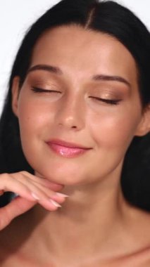 Işıl ışıl cildi ve yumuşak doğal makyajı olan, elleriyle nazikçe poz veren kendine güvenen bir kadının yakın portresi. Güzellik, cilt bakımı ya da kozmetik ürünler için mükemmel.. 