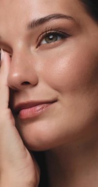 Kusursuz derisi ve doğal makyajı olan, yüzüne nazikçe dokunan bir kadının çarpıcı yakın çekimi. Güzellik, cilt bakımı ve sağlıklı, parlayan deriyi destekleyen sağlık kavramları için ideal.. 