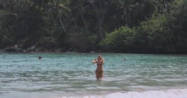 Hiriketiya Sahili, Sri Lanka 'da bikinili bir kadın turkuaz sudan çıkar. Etrafı bereketli palmiye ağaçları ile çevrili bu tropikal cennet, sakin ve egzotik bir deniz kaçışı sunuyor.. 