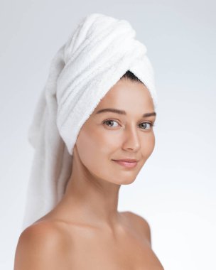 Kusursuz bir cilt ve beyaz bir havlu sarılı genç bir kadın, taze ve ışıl ışıl görünüyor. Cilt bakımı, güzellik, sağlık reklamları ve promosyonlar için mükemmel.. 