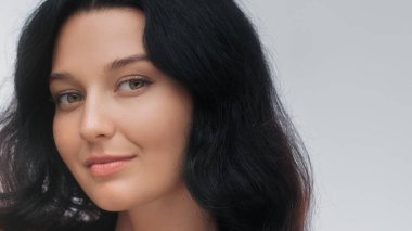 Koyu renk saçlı, parlak tenli, doğal güzellik ve cilt bakımı yapan zarif bir kadının yakın çekimi. Güzellik, sağlık ve kozmetik reklam kampanyaları için mükemmel. Sağlıklı cilt ve kendine odaklı.
