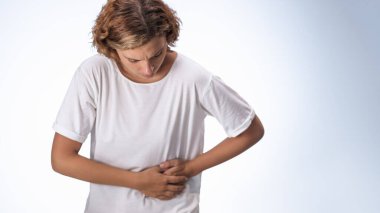 Görünür ağrısı olan genç bir kadın, apandisit, böbrek taşı ya da karaciğer iltihabından kaynaklanan şiddetli iç ağrısını işaret ederek öne doğru eğiliyor. Sağlık hizmetleri veya tanısal kavramlar için harika.