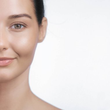 Pürüzsüz, parlak bir teni ve doğal bir gülüşü olan beyaz bir kadının yakın çekimi. Güzellik, cilt bakımı ve sağIık kavramları için mükemmel..