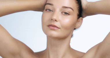 Çıplak omuzlu, parlak tenli, saçlarına hafifçe dokunan bir kadının zarif bir portresi. Güzellik ürünleri promosyonları, cilt bakımı reklamları ve lüks refah içeriği için ideal.