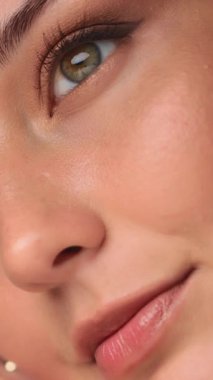 Bir kadının gözünün, dudaklarının ve parlayan teninin aşırı yakın çekimi kusursuz cildini ve doğal güzelliğini ön plana çıkarıyor. Yumuşak ışıklandırma pürüzsüz dokuyu güçlendirir, bu da cilt bakımı için ideal hale getirir.