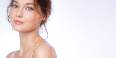 Işıl ışıl, sağlıklı bir teni ve nazik bir gülümsemesi olan genç bir kadının yumuşak ve zarif bir stüdyo portresi. Onun doğal makyajı ve parlayan teni bir sakinlik ve tazelik hissini yansıtıyor. Cilt bakımı için ideal