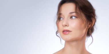 Yumuşak ışıklı bir stüdyoda parlak ciltli ve parlak dudaklı beyaz bir kadının geniş afiş resmi. Güzellik reklamları, cilt tanıtımı, kozmetik afişler ve markalaşma için ideal..