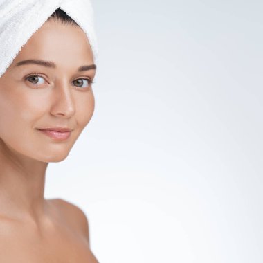 Havluya sarılı parlak tenli genç bir kadın, dingin ve dinç görünüyor. Güzellik, cilt bakımı, kaplıcayla ilgili promosyonlar ve reklamlar için ideal.. 