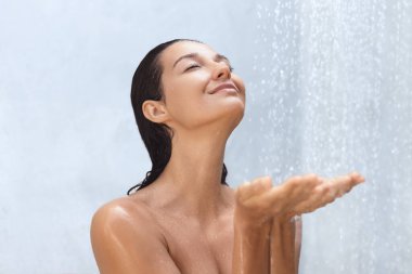  Neşeli bir gülümsemesi ve kapalı gözleriyle dingin bir kadın rahatlamanın ve kendine bakmanın özünü yakalayan ferahlatıcı bir duşun tadını çıkarıyor. Sağlık, cilt bakımı ve kaplıcayla ilgili konular için ideal. 