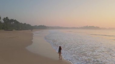 Kaygısız bir kadının Talalla Sahili, Sri Lanka 'da gün doğumunda hafif dalgaların tadını çıkardığı hava görüntüleri. Seyahat, sağlık, ya da mutluluk, özgürlük ve doğa içeren yaşam tarzı kavramları için mükemmel..