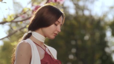 Güneşli bir bahar bahçesinde çiçek açan manolya çiçeğinin kokusunun tadını çıkaran Kafkasyalı genç bir kadının sakin manzarası. Doğa, güzellik, huzur ve refah kavramları için idealdir..