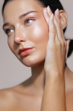 Yüzüne hafifçe dokunan pürüzsüz, parıldayan cildi olan Latin bir kadının yakın çekimi. Cilt bakımı, estetik cerrahi, yaşlanma karşıtı veya kozmetik geliştirmeler için ideal. 