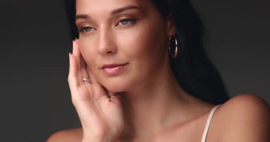 Ağır çekimde yüzüne hafifçe dokunan bir kadının yüksek kaliteli yakın çekim stüdyosu. Cilt bakımı, lüks güzellik reklamları, kozmetik kampanyaları ve yayın tanıtımı için mükemmel..