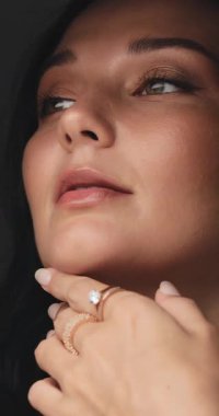 Yavaş çekimde, şık bir kadının boynunu okşaması, altın göz makyajı ve güzel mücevherler sergilemesi. Güzellik, lüks moda veya üst düzey kozmetik reklamları için ideal..