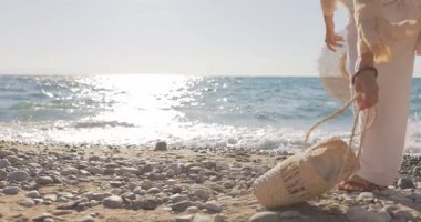 Kayalık bir sahilde duran genç bir kadın, kollarını okyanus esintisinin ve güneş ışığının dalgaları yansıtmasının tadını çıkarmak için açmıştı. Yaşam tarzı, seyahat ve görsel farkındalık için mükemmel.. 