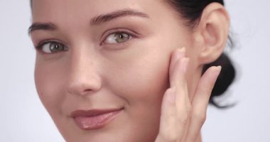 Beyaz kadın, cildine dokunurken gülümsüyor ve cilt bakımı sonuçlarını gösteriyor. Görseller, kozmetik dermatoloji ve cilt bakımı için ideal.
