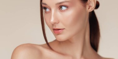 Zarif bir güzellik afişi, parlak ciltli ve zarif makyajlı genç bir bayanı yana doğru gösteriyor. Cilt bakımı, kozmetik reklamlar ve sağlık kampanyaları için mükemmel. Temiz stüdyo ayarı.