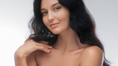 Çıplak omuzlu zarif esmer kadın stüdyo ortamında zarifçe poz veriyor. Yumuşak gülüşü ve rahat ifadesi doğal güzelliğini ön plana çıkarıyor. Bu görüntüyü güzellik, cilt bakımı ve...