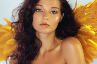 Altın melek kanatları ve çıplak omuzları olan şehvetli bir kadının büyüleyici portresi. Moda, güzellik ve kavramsal tanıtım temaları için yüksek kalite görüntü mükemmeldir..