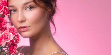 Zarif yatay pankart, güzel bir kadının taze pembe karanfiller ve parlayan ciltle poz verdiğini gösteriyor. Çiçek temalı güzellik reklamları, cilt tanıtımları ve kozmetik ürünler için ideal..