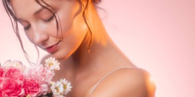 Zarif bir kadın elinde karanfil buketi ve gözleri kapalı papatyalar tutuyor. Yumuşak ışık ve kadınsı güzellik saçıyor. Güzellik, cilt bakımı ve romantik çiçek teması için ideal..