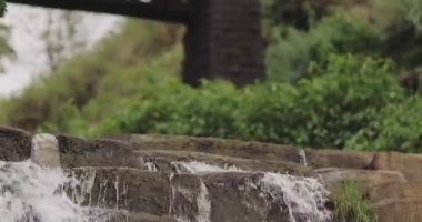 Sri Lanka 'daki Galwala Ella Şelalesi' nin manzaralı bir manzarası. Üzerinden okul çocuklarının geçtiği bir demiryolu köprüsü var. Şelale şelalesi ve bereketli çevresi resimlerle dolu, doğal bir ortam yaratır.