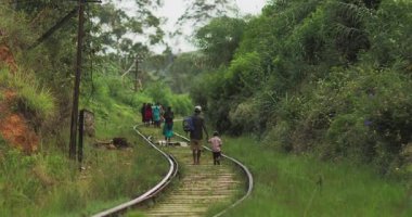 İnsanlar Nuwara Eliya, Sri Lanka 'nın yemyeşil manzarasıyla çevrili demiryolu raylarında yürüyor. Bu resim, taşra seyahatlerinin basitliğini ve güzelliğini, seyahat, kültür ve...