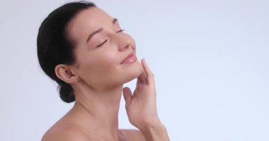 Kendine güvenen beyaz kadın, minimalist bir cilt bakımında pürüzsüz tenine dokunur. Dermatoloji klinikleri, yaşlanma karşıtı tedaviler, yüz bakımı ve kozmetik gençleştirme hizmetleri için mükemmel..