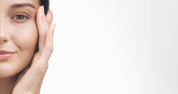 Высококачественный крупный план светящегося лица женщины с прикосновением руки к щеке и просторным белым пространством для рекламного текста. Идеально подходит для рекламы по уходу за кожей, баннеров, оздоровительного брендинга и косметики.