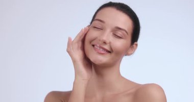 Zarif, beyaz tenli bir kadın nazikçe çenesine dokunuyor. Yüksek kaliteli bir güzellik konsepti videosu çekiyor. Cilt bakımı, kozmetik reklamları ya da sağlık reklamları için ideal..