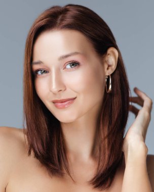 Beyaz tenli, yumuşak makyajlı ve halka küpeli beyaz bir kadının kaliteli stüdyo portresi. Güzellik, cilt bakımı ve hayat tarzı tanıtımları için ideal..