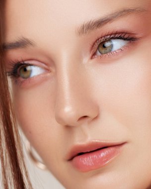 Genç, beyaz tenli, yeşil gözlü ve parlak dudaklı bir kadının zarif yakın plan portresi. Güzellik ürünleri reklamları, cilt ürünleri ve üst düzey kozmetik ürünleri için mükemmel bir imaj..