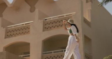 Şık bir kadın güneşli bir günde lüks bir Mısır tatil köyünde yürüyor. Seyahat, tatil ve yaşam tarzı temaları için mükemmel. Huzurlu bir ortamda zarafet ve entelektüellik vurgulanıyor.. 