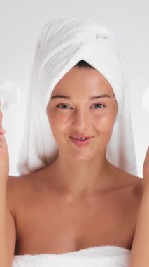 Havlu ve sarıklı genç beyaz kadın güzellik rutini sırasında pamuk pedlerle oynuyor. Cilt bakımı, yüz bakımı, kozmetik ürünleri ve taze sabah sağlığı tanıtımı için ideal..