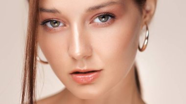 Yüksek çözünürlüklü beyaz tenli, parlak çıplak dudaklı ve halka küpeli genç bir kadının yakın çekimi. Makyaj, cilt bakımı, lüks güzellik ürünleri reklamcılığı ve editörlük için ideal..