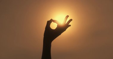 Güneş doğarken yoga Mudra 'sı oluşturan bir elin yakın çekimi. Refah, farkındalık, meditasyon veya iç huzur temaları için kavramsal ve ruhani stok görüntüleri.