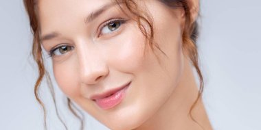 Parlak bir cilt ve parlak dudaklarla gülümseyen genç bir kadının zarif yakın plan portresi. Yüz bakımı, doğal kozmetik ürünleri ve kadın sağlığı ve yaşam tarzı kampanyaları için ideal..