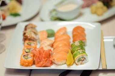 Taze nigiri ve rulo çeşitleri içeren bir gurme suşi tabağı. Beyaz bir tabakta güzelce sunuluyor. Japon mutfağını vurgulamak için mükemmel, güzel yemek deneyimleri, ve lüks