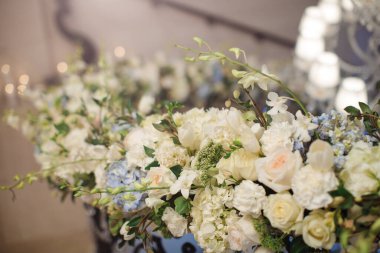 Güller, orkideler ve orkideler içeren güzel beyaz çiçek aranjmanları, düğünler ve zarif etkinlikler için mükemmel. Lüks, romantizm ve kutlama temaları için ideal, sofistike sergilenen