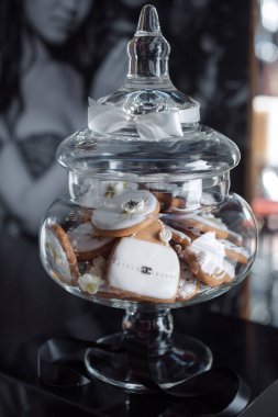 Dekoratif cam bir kavanozda beyaz ve altın temalı kurabiyelerin sofistike bir gösterisi. Üst düzey etkinlikler, düğünler ve lüks kutlamalar için ideal, gösterişli tasarım ve zarafet.